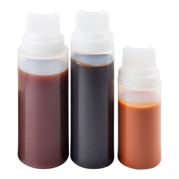 A set of three plastic squeeze bottles with wide mouths and dual-tip tops, each filled with different sauces.