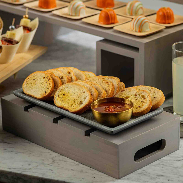 A gray wood serving and display crate holding a platter of sliced bread and a bowl of dip.