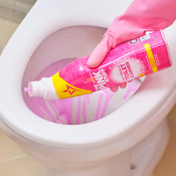 A bottle of The Pink Stuff Miracle Toilet Cleaner Gel being applied to a toilet bowl.
