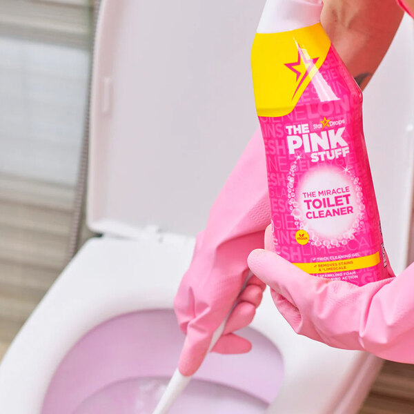 A bottle of The Pink Stuff Miracle Toilet Cleaner Gel being used to clean a toilet.