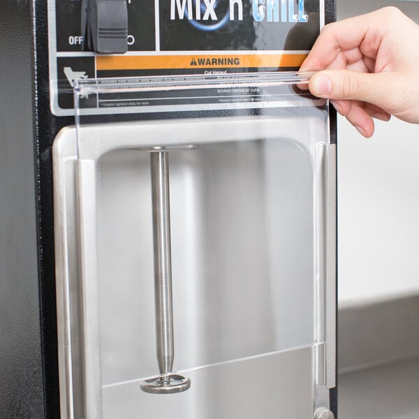 A hand holding a plastic cover over a small container of mix.