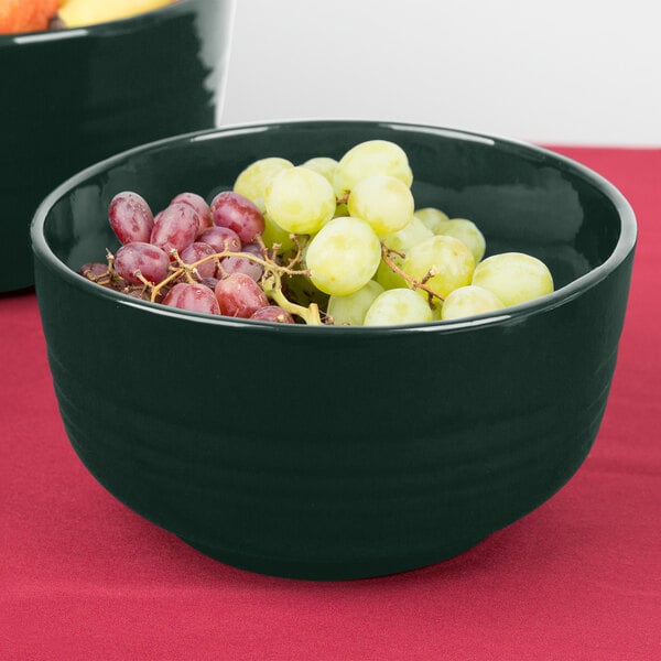 A Tablecraft hunter green cast aluminum fruit bowl filled with grapes.