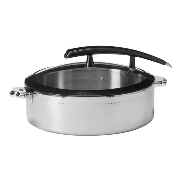 A round, hammered steel pot with a glass lid and a large, curved black handle.