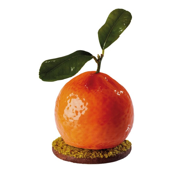 A glossy, orange, tangerine-shaped dessert with two green leaves on top, sitting on a round base with a crumbly texture.