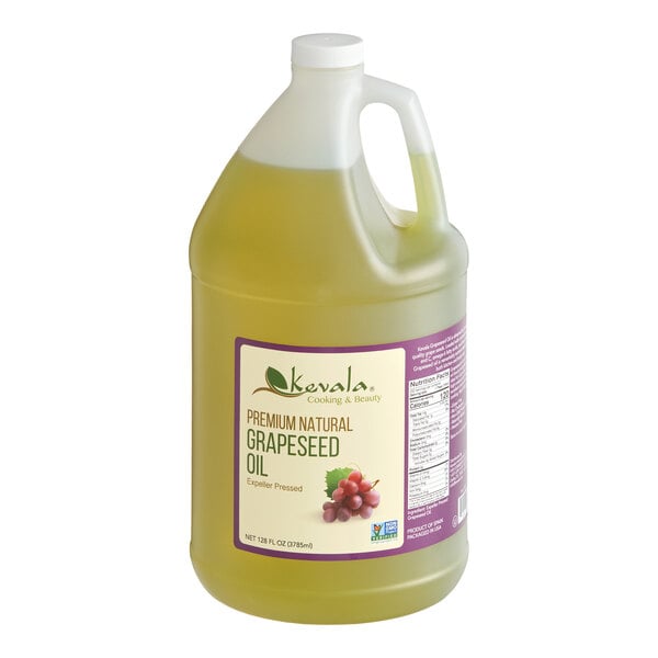 A large, clear plastic jug filled with light yellow liquid, labeled as Kevala Premium Natural Grapeseed Oil, with a handle and a white cap.
