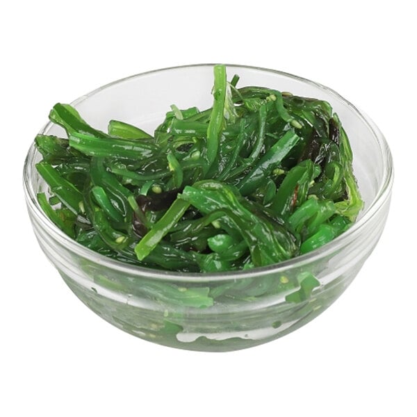 A glass bowl filled with green seaweed salad.