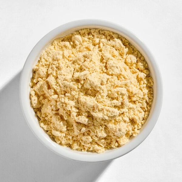 A white bowl filled with a light yellow, crumbly powder on a white surface.