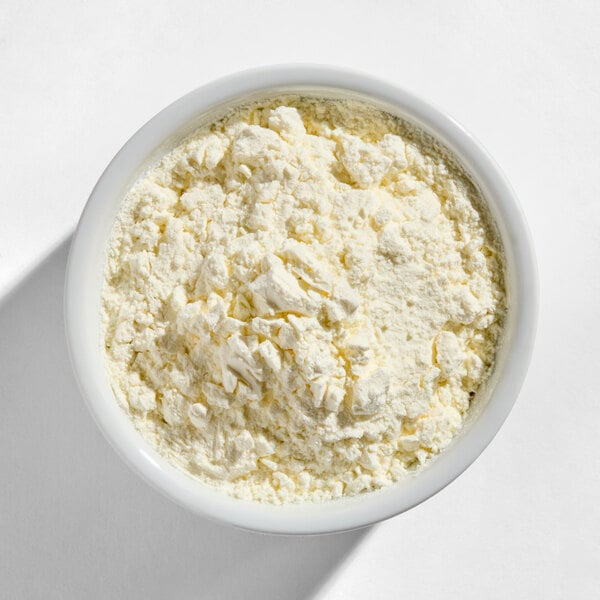 A white bowl filled with a pale yellow, powdery substance with some small clumps.