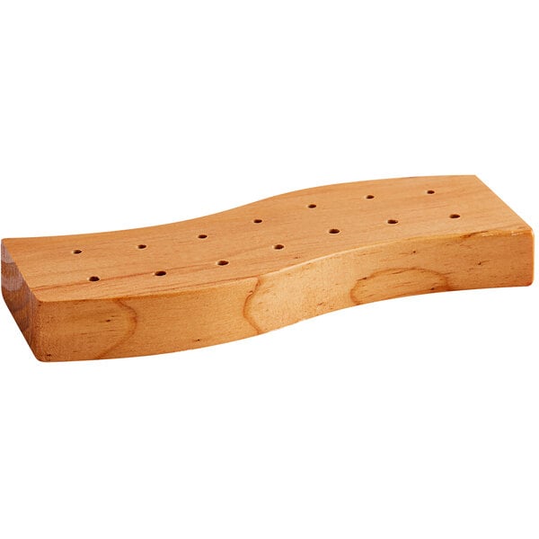 A rectangular, wave-shaped wooden block with fourteen evenly spaced holes on the top surface.
