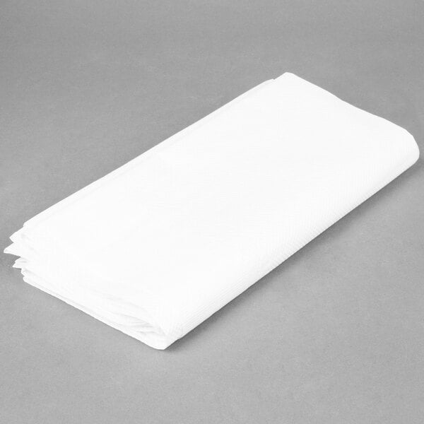 A folded white tissue/poly table cover on a gray surface.