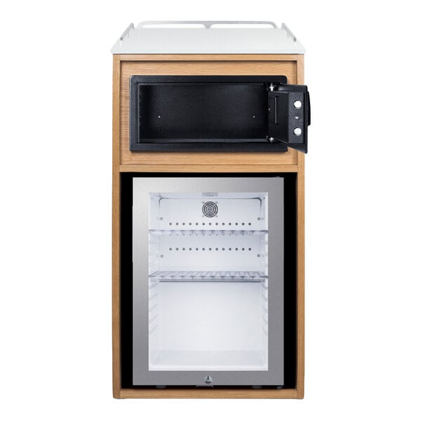 A wooden cabinet features a glass door minibar refrigerator on the bottom and an open black safe above it.