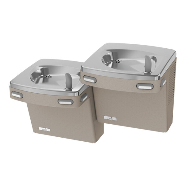 Two bi-level drinking fountains with a sand-colored base and stainless steel basins, each featuring a water spout and push bars.