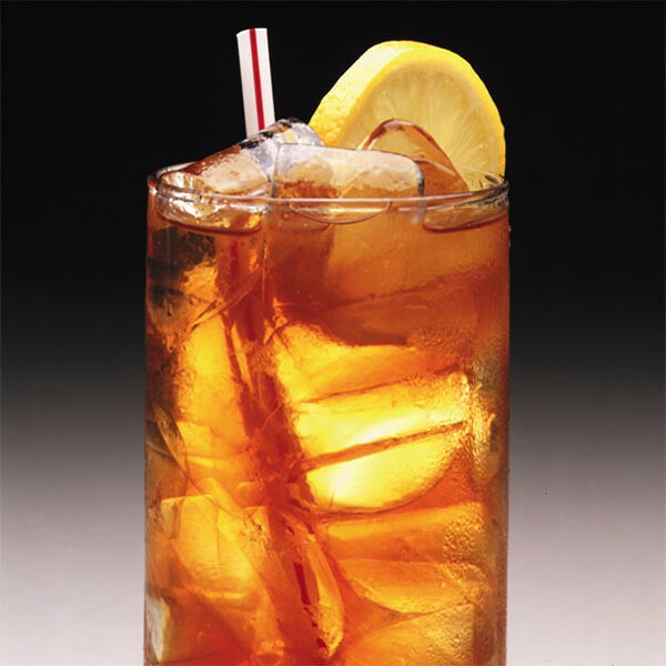 A glass filled with iced tea, ice cubes, a lemon wedge, and a straw.