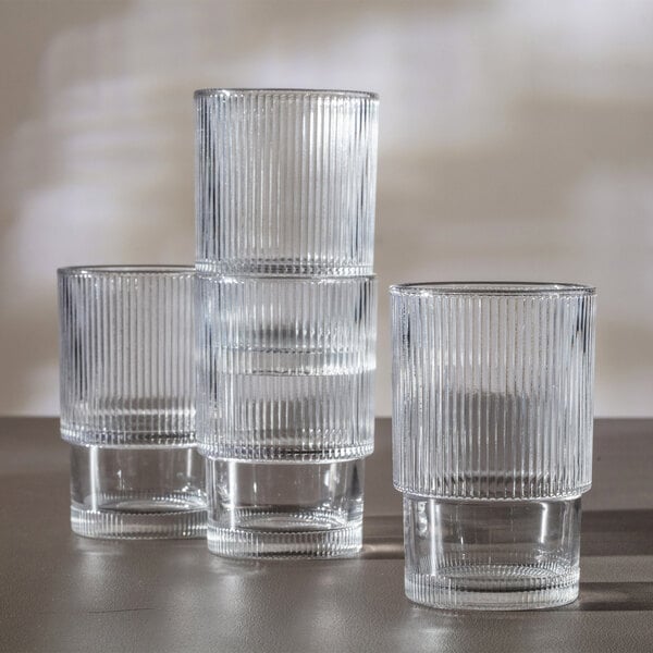 Four clear, vertically ribbed drinking glasses are shown, with two of them stacked on top of each other.