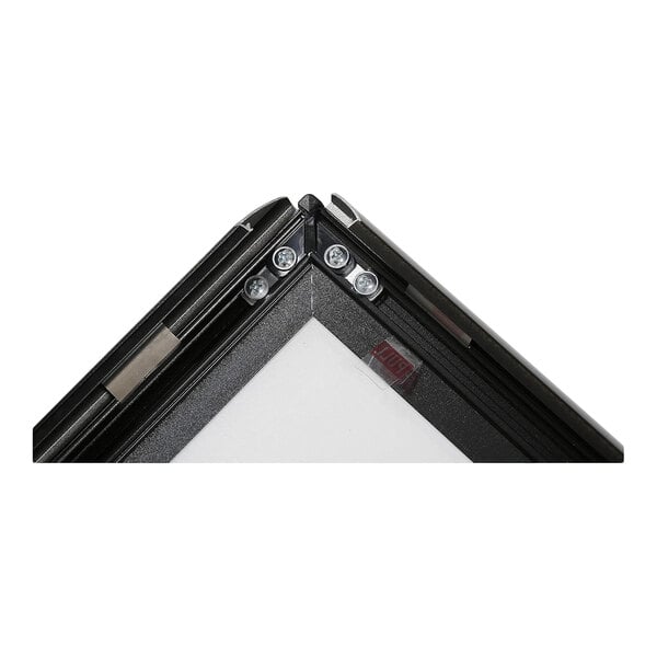 A close-up view of the corner of a black metal frame with visible screws and a white panel inside.