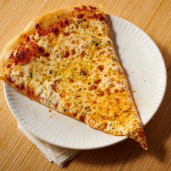 A large slice of cheese pizza on a white plate, resting on a wooden surface with a napkin underneath.