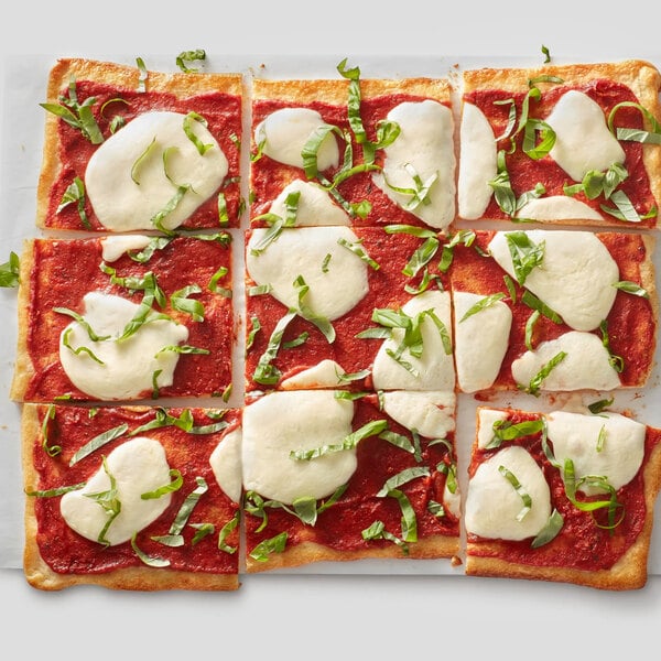 A rectangular pizza cut into nine square slices, topped with tomato sauce, melted mozzarella cheese, and fresh basil strips.