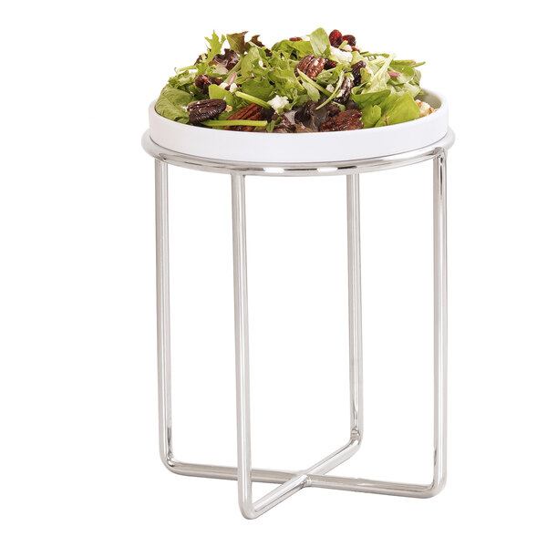 A round white bowl filled with salad is placed on a tall, chrome wire stand with a modern, open-frame design.