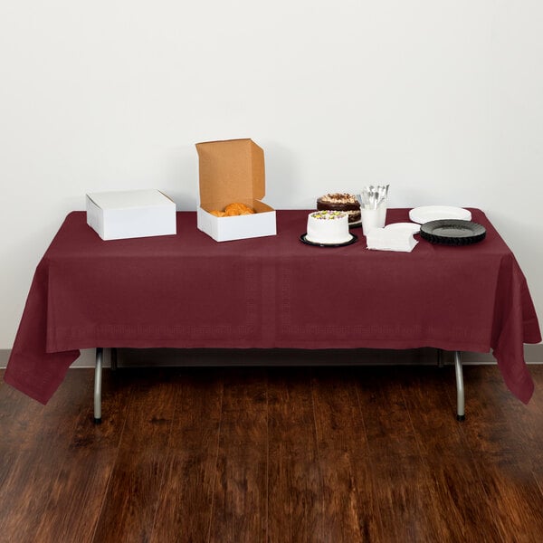 A table with a Creative Converting burgundy table cover with food on it.