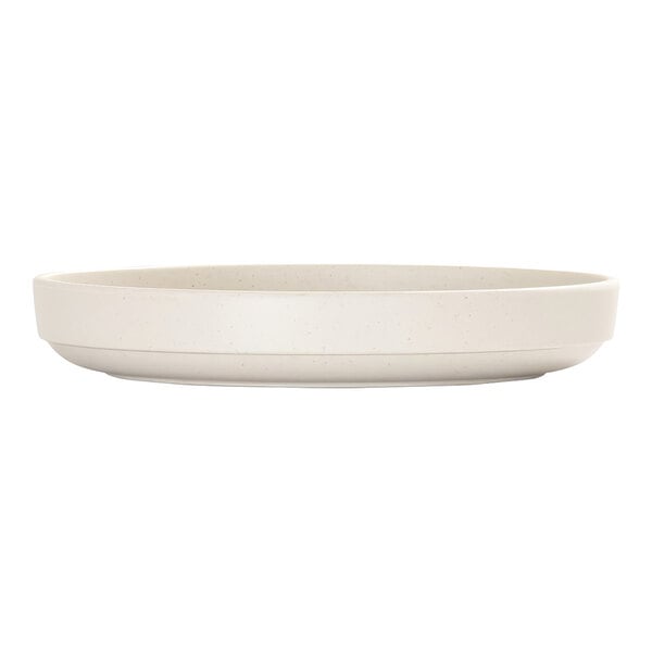 A round, ivory-colored plate with a raised rim and subtle speckled pattern, shown from the side.