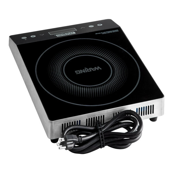 A black and silver countertop induction cooktop with a circular cooking zone and a coiled power cord placed in front.
