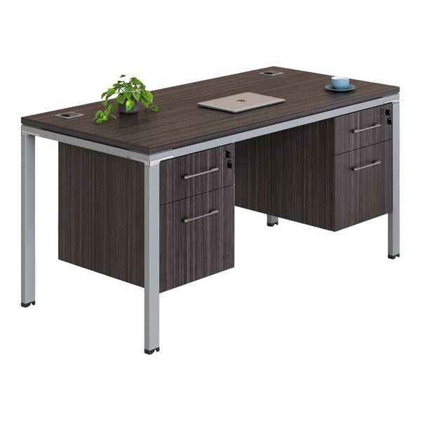 A modern office desk with a dark wood-like finish, metal legs, two sets of drawers, a laptop, a small plant, and a cup on top.