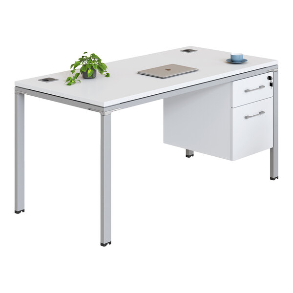 A modern white desk with metal legs, featuring a small potted plant, a closed laptop, a cup and saucer, and two drawers on the right side.