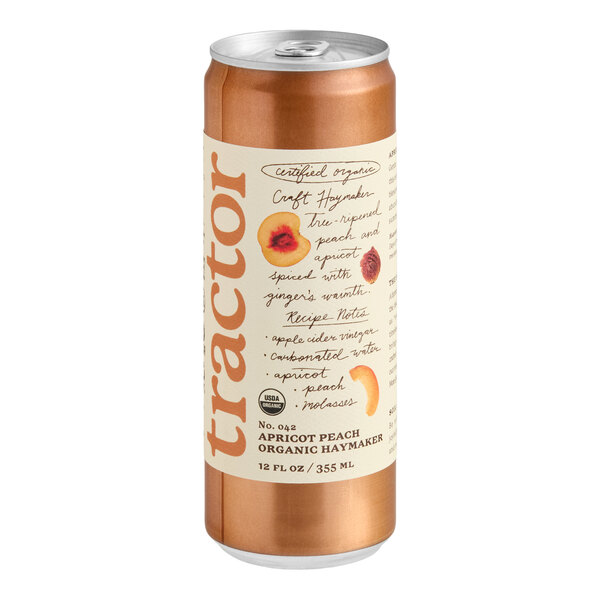 A tall, metallic can with a cream-colored label featuring the word 'tractor' vertically, fruit illustrations, and handwritten-style text describing an apricot peach organic beverage.