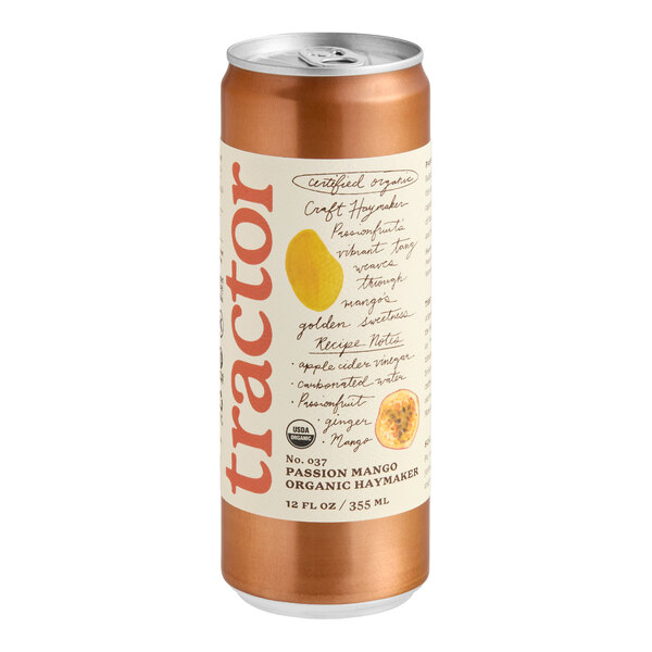 A metallic orange can with a cream-colored label featuring the word 'tractor' in large red letters, fruit illustrations, and handwritten-style text describing the passion mango flavor.