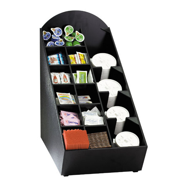 A black countertop organizer with multiple compartments holding coffee cup lids, condiment packets, creamers, stirrers, and napkins.
