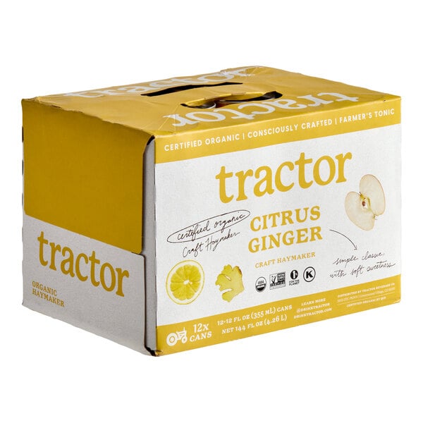 A cardboard box with yellow and white design labeled 'tractor citrus ginger' containing 12 cans, featuring images of lemon, ginger, and apple slices.