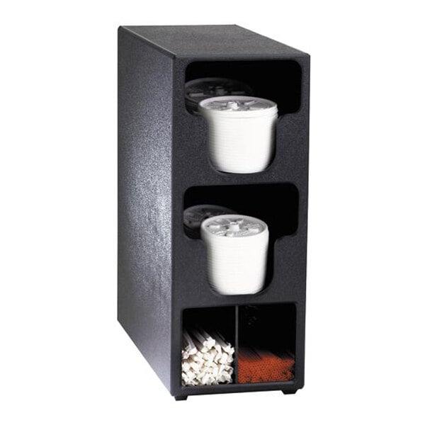 A black vertical organizer with two upper compartments holding stacks of white plastic lids and two lower sections containing straws and stirrers.