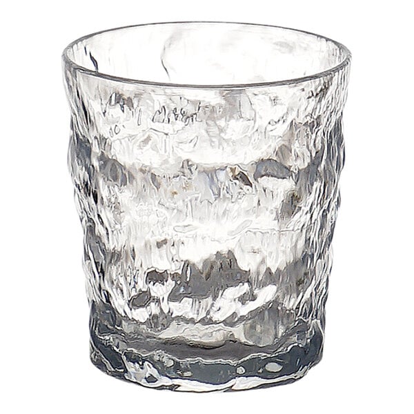 A clear drinking glass with a textured, wavy surface and a thick base.