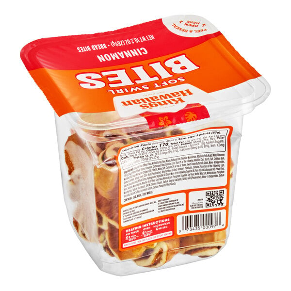 A clear plastic container with a red and orange lid, filled with small cinnamon roll bites and labeled with nutritional information and heating instructions.