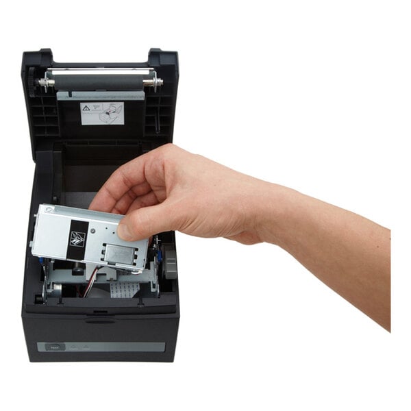 A hand is installing or removing a metallic component inside an open black electronic device, possibly a printer.