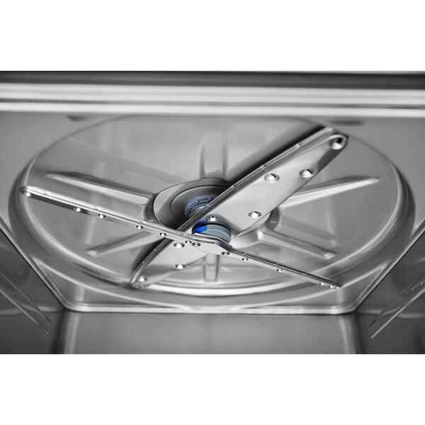 A close-up view of the interior spray arm and base inside a stainless steel dishwasher.