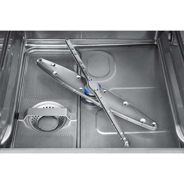 A close-up view of the interior of a stainless steel dishwasher, showing the spray arms and filter area.