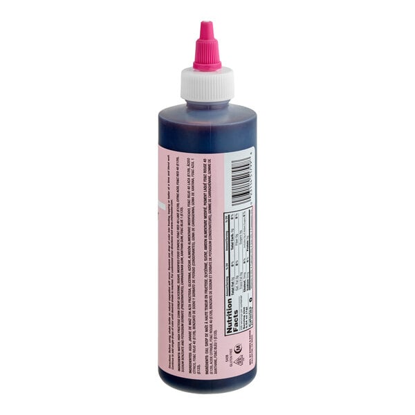 A plastic squeeze bottle with a pink label and a pink-tipped white cap, containing a dark liquid, shown with nutritional information and text on the label.