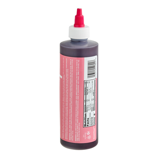 A plastic squeeze bottle with a pink label, white cap, and red nozzle, containing a dark liquid and displaying nutrition facts and a barcode.