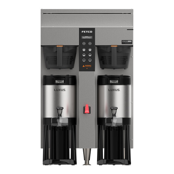 A front view of a large, stainless steel twin automatic coffee brewer with two metal brew baskets and two insulated dispensers labeled 'LUXUS.'