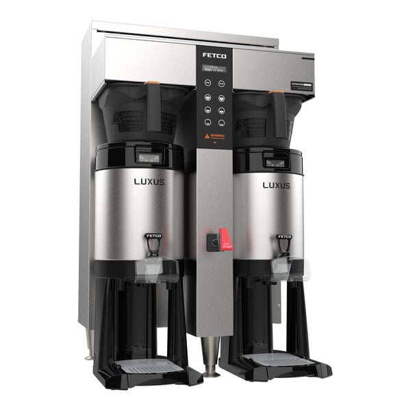 A large, stainless steel twin coffee brewer with digital controls and two insulated dispensers labeled 'LUXUS.'