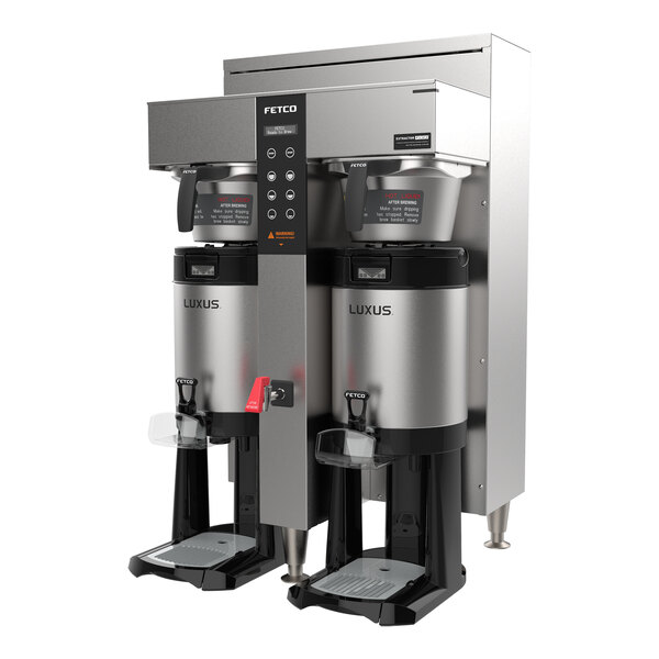 A stainless steel twin automatic coffee brewer with two large insulated dispensers and digital controls on the front panel.