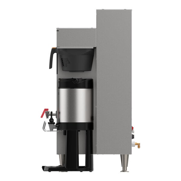 A side view of a commercial coffee brewing machine with a metal brew basket and a stainless steel airpot beneath it.