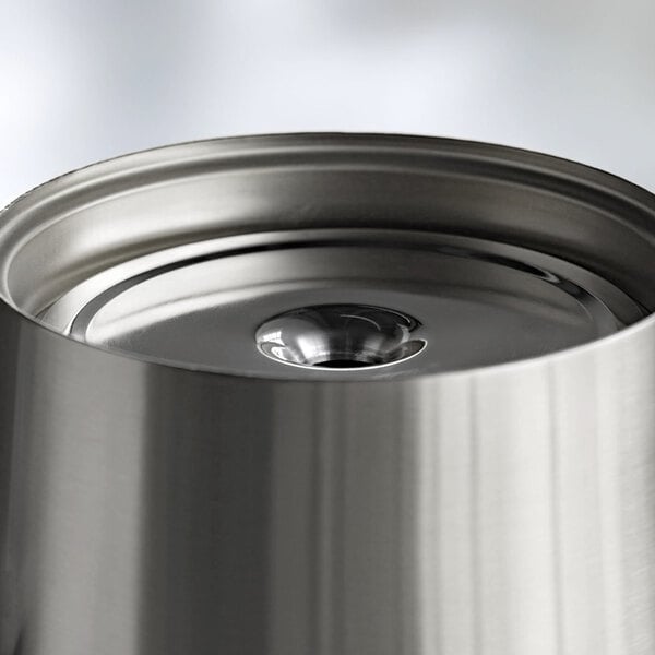A close-up view of a brushed stainless steel container with a reflective, circular lid.