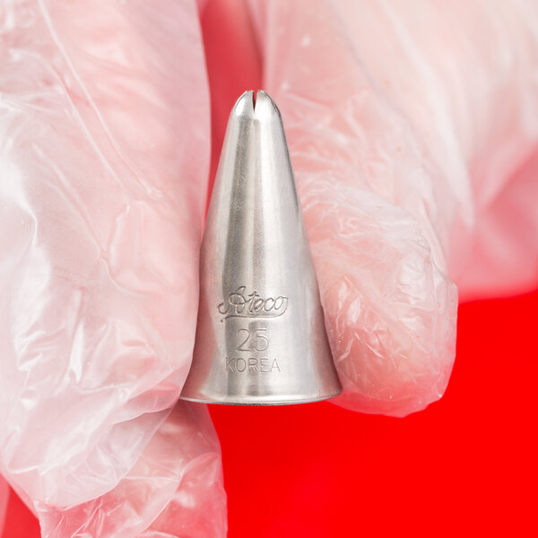A gloved hand is holding a metal piping tip with a closed star opening against a red background.