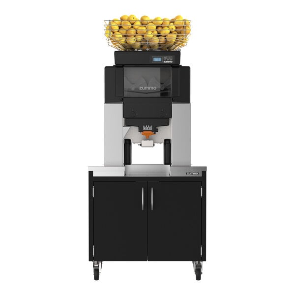 A commercial juicer machine with a basket of lemons on top, mounted on a black cabinet with double doors and wheels.