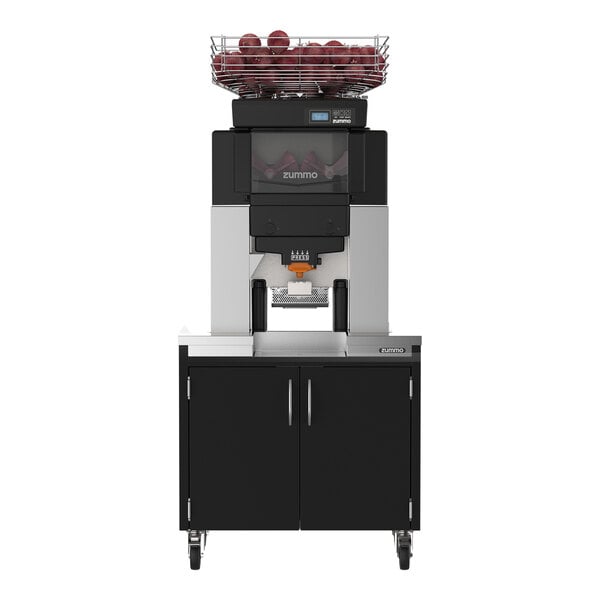 A commercial juicer machine with a fruit basket on top, mounted on a black cabinet with double doors and wheels.