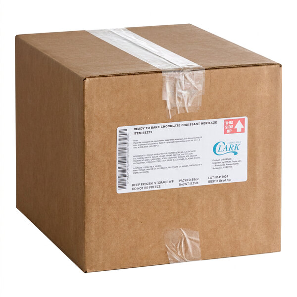 A sealed brown cardboard box with a white label and clear tape, marked for ready-to-bake chocolate croissants.