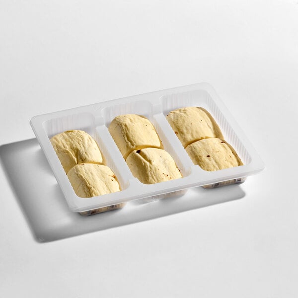 A plastic tray containing six unbaked, rectangular pastries with a light, doughy appearance.