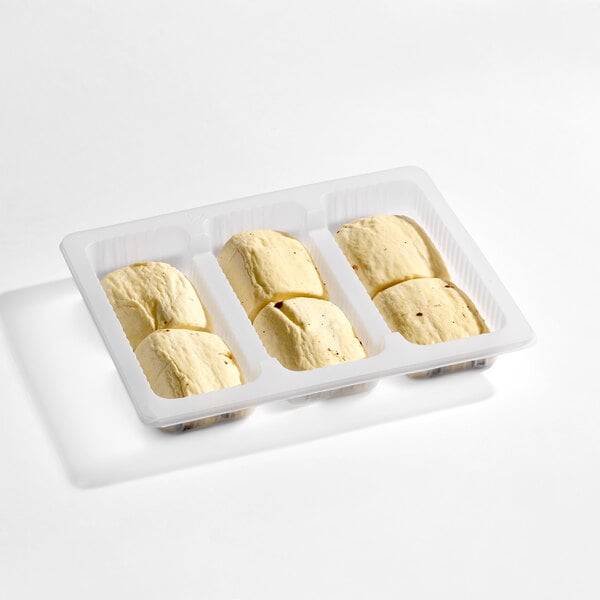 A white plastic tray containing six unbaked, rectangular pastry dough pieces.